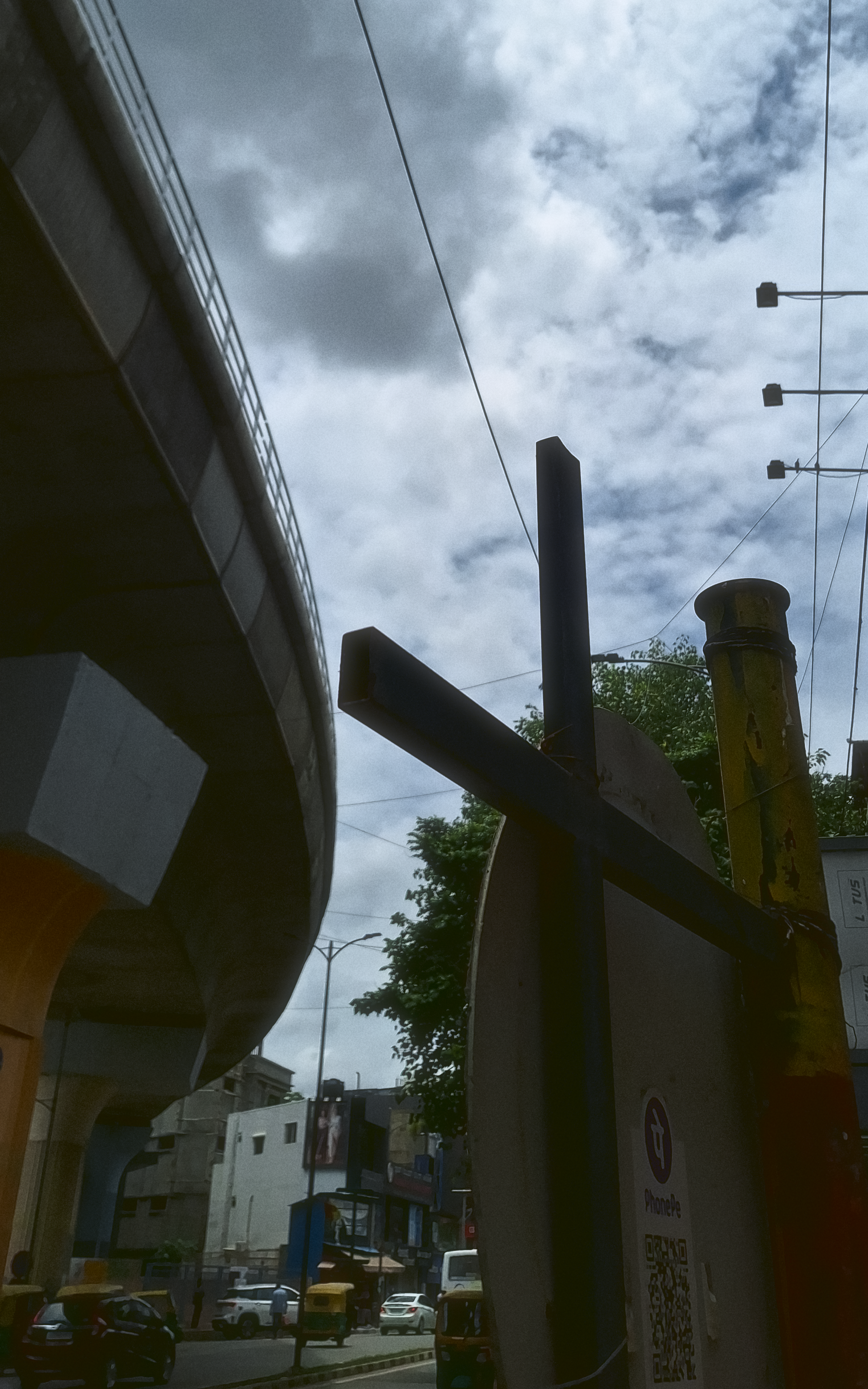 A photo of an elevated metro line on the top left, and a road on the bottom. A sign creeps into the frame on the right, with a PhonePe QR code on it.